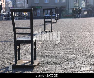 Cracow. Krakow. Poland. Former Cracow`s ghetto in Podgorze district. The Ghetto Heroes Square with the memorial in the form of sculptured chairs. Stock Photo